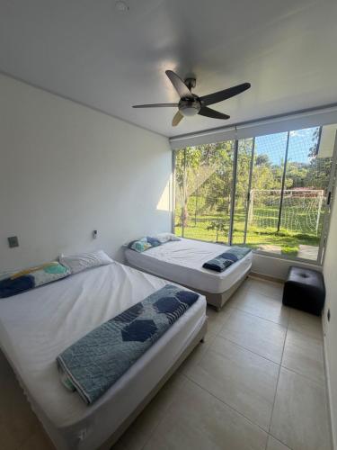 two beds in a room with a ceiling fan at Finca para estrenar in Anapoima