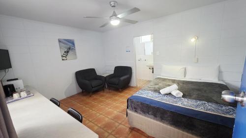 a bedroom with a bed and two chairs in a room at Sunburst Motel in Gold Coast