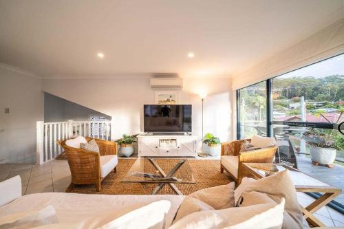 a living room with a couch and a tv at Avoca Beachside Retreat in Avoca Beach