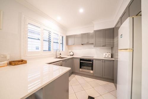 a kitchen with gray cabinets and a white refrigerator at Avoca Beachside Retreat in Avoca Beach