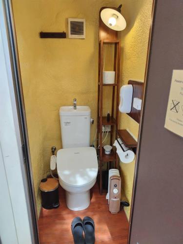 a small bathroom with a toilet and a pair of shoes at Tsunagaru Camp Resort QOONEL+ in Fujikawaguchiko