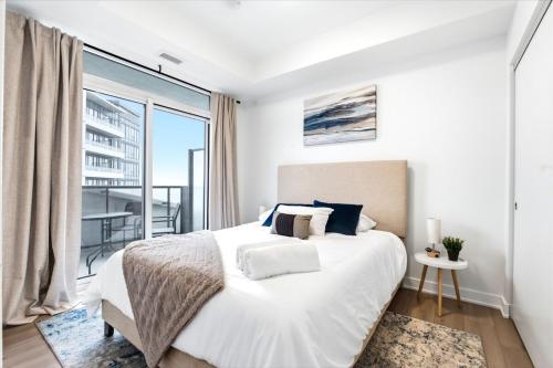 a white bedroom with a bed and a large window at Stylish Skyview Condo in Kitchener Downtown in Kitchener