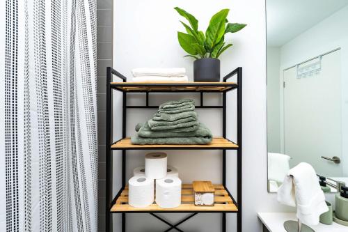 a bathroom with a shelf with towels and a plant at Stylish Skyview Condo in Kitchener Downtown in Kitchener
