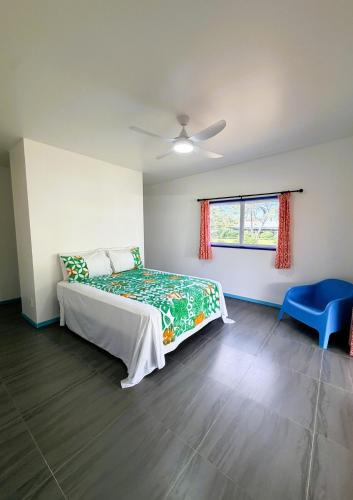 a bedroom with a bed and a blue chair at Kuki Kainga in Matavera