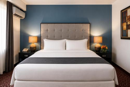 a bedroom with a large bed with a blue wall at KC Hotel San Jose in San José
