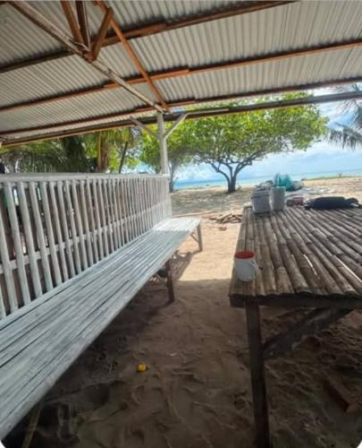 a wooden bench sitting under a roof on the beach at Hatch Guesthouse in Ocoy