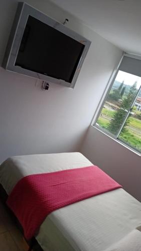 a bedroom with a flat screen tv above a bed at Bello apto en armenia 1306 in Armenia
