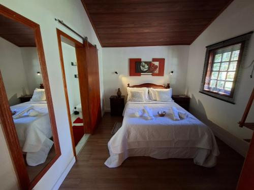 ein Schlafzimmer mit zwei Betten und einem großen Spiegel in der Unterkunft Chalé Cabana Ruby in Gonçalves