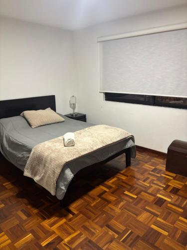 a bedroom with a bed with a window and a wooden floor at DEPARTAMENTO DUPLEX 3 Habitaciones EN CUENCA ECUADOR in Cuenca