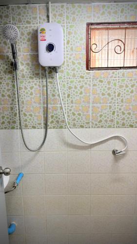 a bathroom with a shower with a blow dryer on the wall at Traditional Thai House Chaloklum in Chaloklum