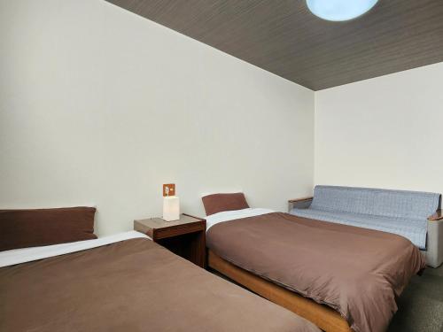 a room with two beds and a table with a lamp at Pension Kobekko in Otari