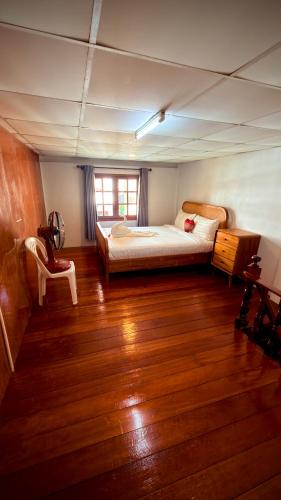 a bedroom with a bed and a wooden floor at Traditional Thai House Chaloklum in Chaloklum