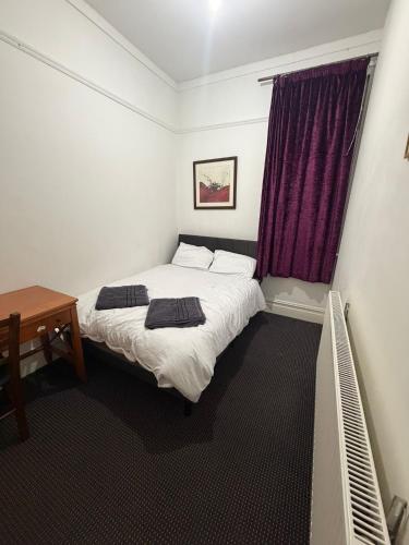 a bedroom with two beds and a table and purple curtains at The Navigation Inn Hotel in Derby