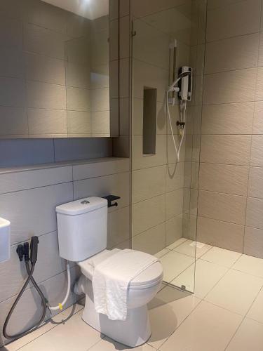 a bathroom with a shower with a toilet and a phone at Roxy Hotel Selangau in Rumah Kudan