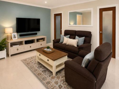 a living room with two couches and a flat screen tv at William's on William - Stylish 2 Bedroom Haven in Ormiston