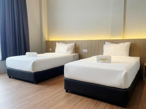 two beds sitting next to each other in a room at Roxy Hotel Selangau in Rumah Kudan