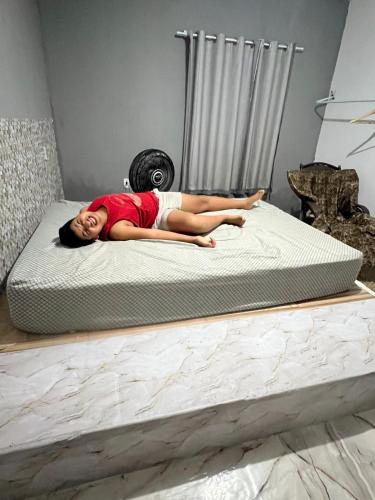 a woman laying on a firm mattress on a bed at Casa com piscina in Belfort Roxo