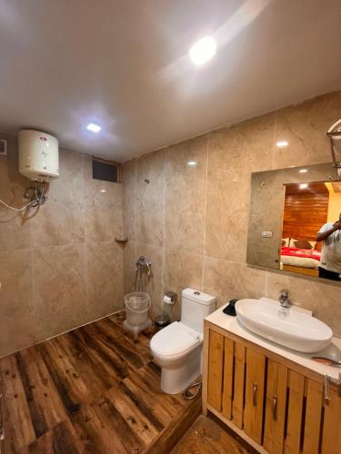 a bathroom with a white toilet and a sink at Orchard Valley Resort in Mai Jūbar