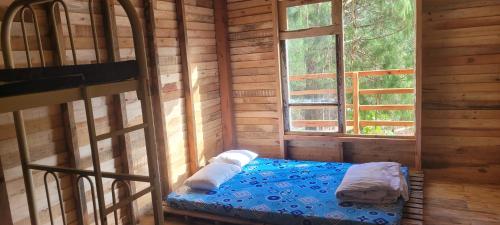 a room with a bed in a wooden cabin at Mộc Tín Farmstay in Lạc Dương