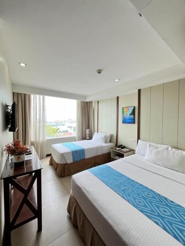 a hotel room with two beds and a window at Belian Hotel in Tagbilaran City