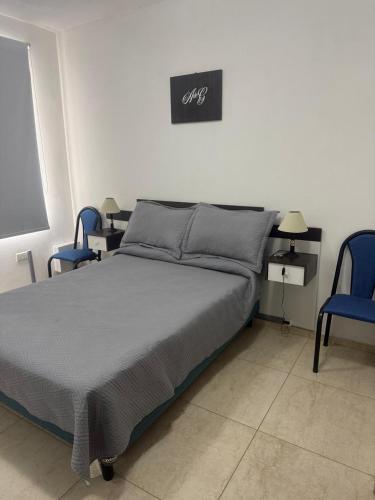 a bedroom with a bed and two blue chairs at Acordes de Gaitas - Departamento 2 in Malargüe