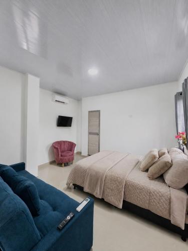 a bedroom with a large bed and a blue couch at Sol caribe aptos in Santiago