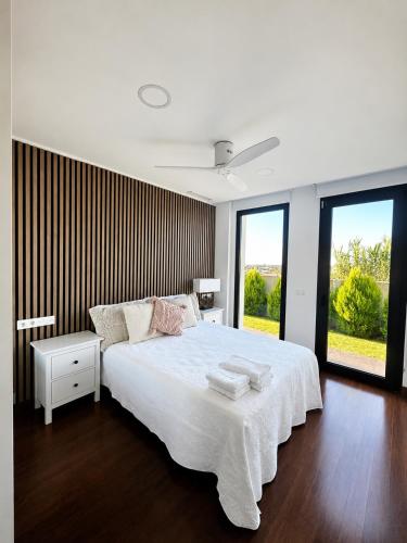 a bedroom with a large white bed and windows at Puesta de Sol Doñana Adults Only in Sanlúcar de Barrameda