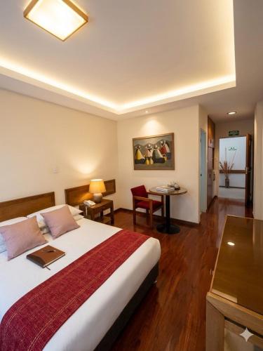 a hotel room with a large bed and a desk at Hotel Boyaca Plaza in Tunja