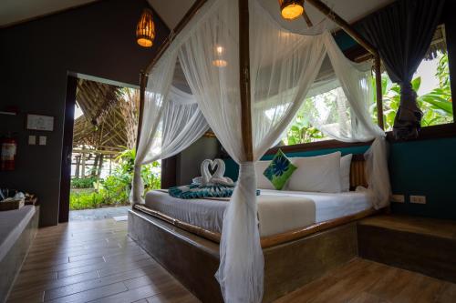 a bedroom with a canopy bed with white curtains at Buko Beach Resort in El Nido