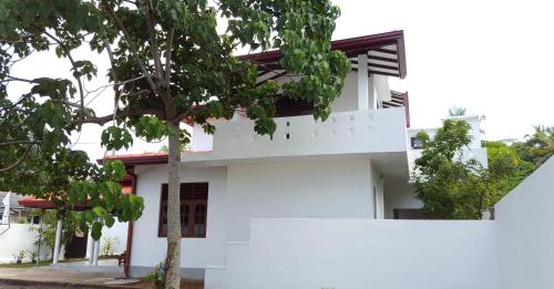 a white house with a tree in front of it at Emildale Villa in Wadduwa