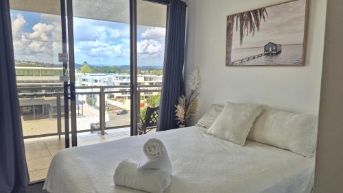 a bedroom with a white bed and a large window at Trafalgar Towers in Maroochydore