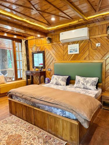 a bedroom with a large bed in a room with wooden walls at Arcelia Cottage, Cozy Villa in Nainital in Nainital