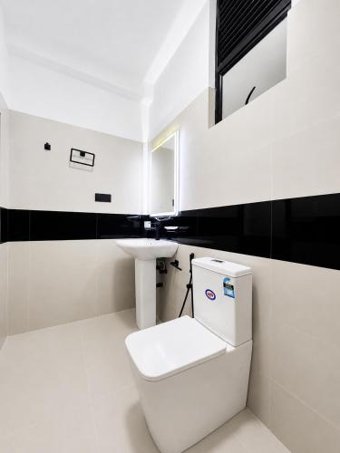 a white bathroom with a toilet and a sink at Villa 777 in Kadawata