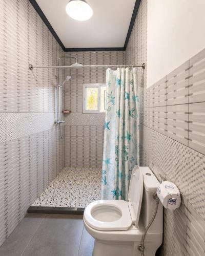 a white bathroom with a toilet and a shower at KFC Homes in Yaoundé