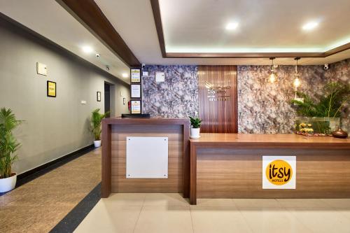 a reception desk in a lobby with a white sign at Itsy Hotels Emirates Suites - Near RMZ EcoWorld, Bellandur in Bangalore