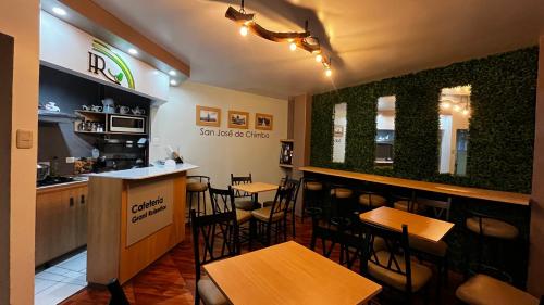a restaurant with a bar and tables and chairs at Hotel Grant Ruiseñor in Chambo