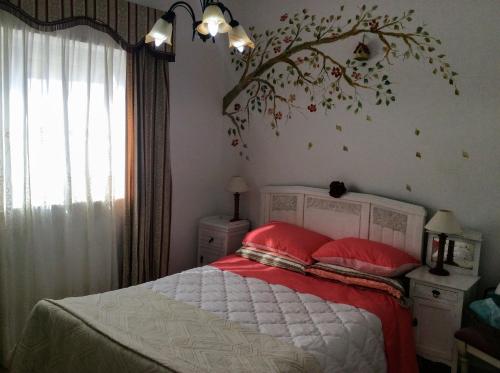 Un dormitorio con una cama con almohadas rojas y una rama en la pared en Villa da Melis, en Buarcos