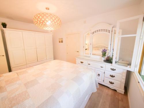 a bedroom with a bed and a dresser and a chandelier at Chalet La Caballa Playa la Barrosa in Chiclana de la Frontera