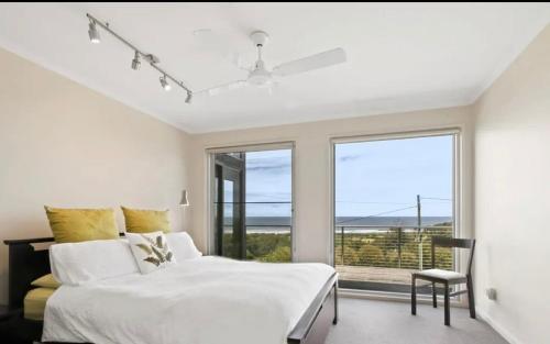 a bedroom with a white bed and a large window at Marcail Views Lakes Entrance in Lakes Entrance
