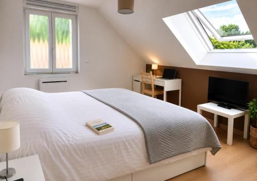a white bedroom with a bed and a television at Horizons du Haut in Niederbronn-les-Bains