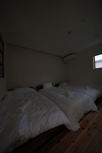 two large white beds in a room with a window at 紀の川みんと静 in Kinokawa