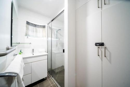 a white bathroom with a shower and a sink at Comfy Kirwan Getaway in Ross River