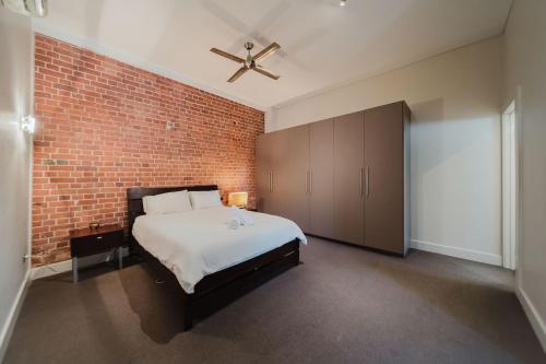 a bedroom with a brick wall and a bed at Flinders 2 bed apartment near the Strand in Townsville