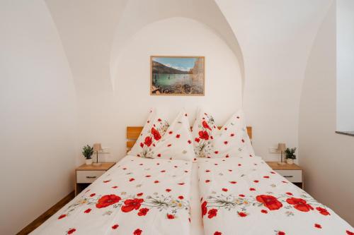 a bedroom with a bed with red flowers on it at Peak9 Apartment in Greifenburg