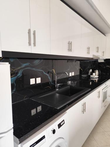 a kitchen with a sink and white cabinets at M&J Home in Ksamil