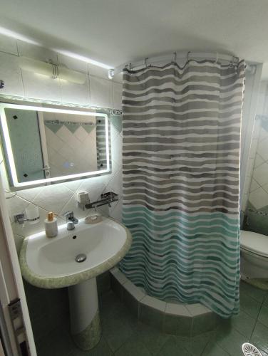 a bathroom with a sink and a shower curtain at M&J Home in Ksamil