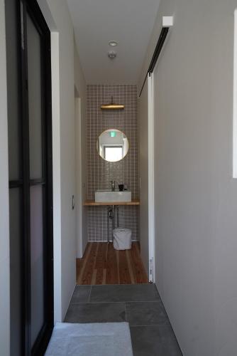 a hallway with a bathroom with a sink and a mirror at 紀の川みんと景 in Kinokawa