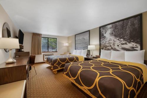 a hotel room with two beds and a desk at Super 8 by Wyndham Cody in Cody
