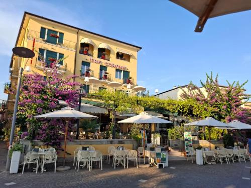 a hotel with tables and umbrellas in front of a building at Hotel Tre Corone in Garda