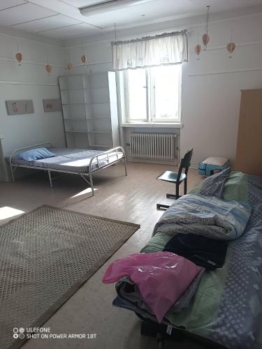 a room with two beds and a chair and a window at Tattara School Room 2 in Nakkila